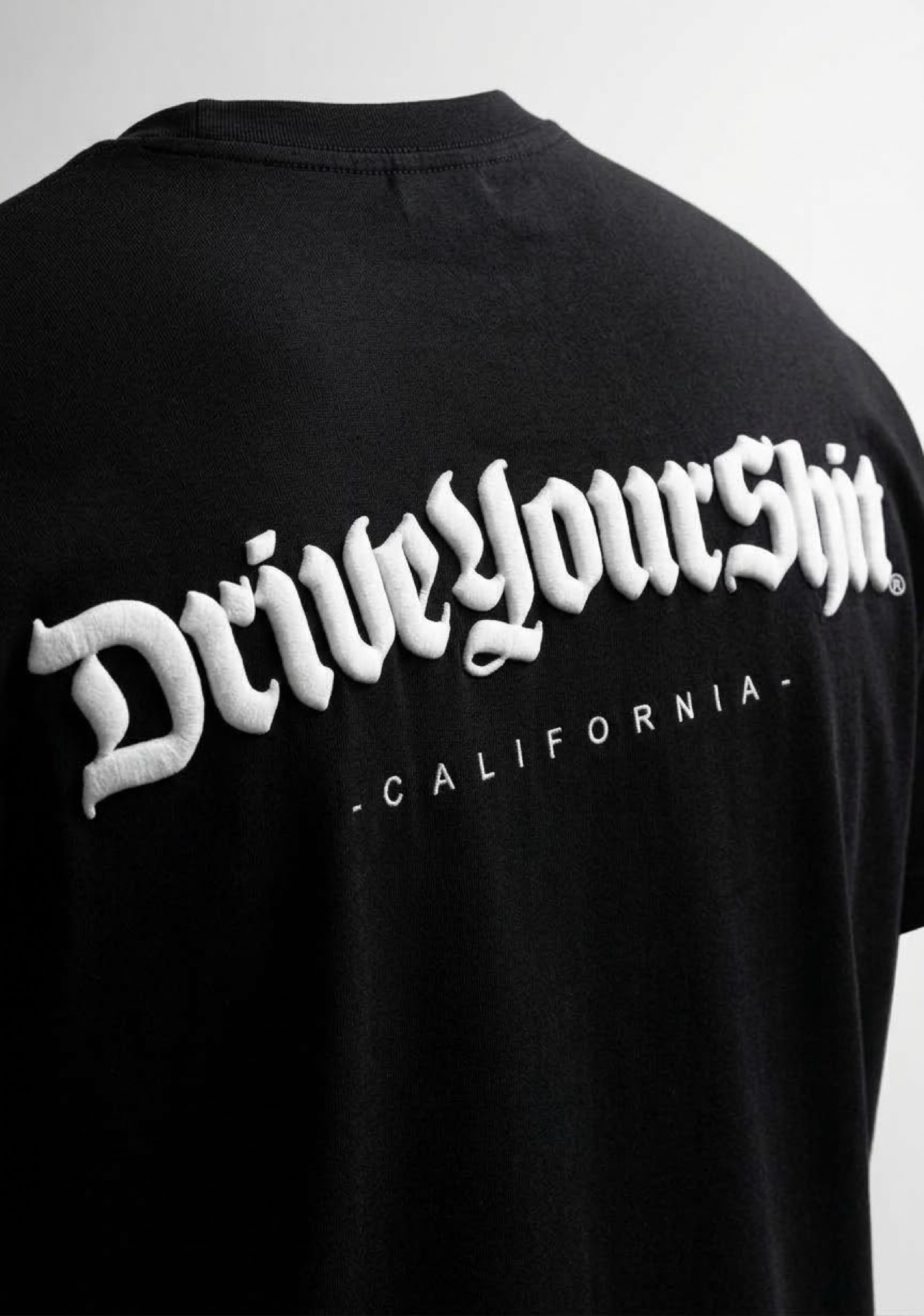 Close-up of the white puff DriveYourShit lettering on a black t-shirt